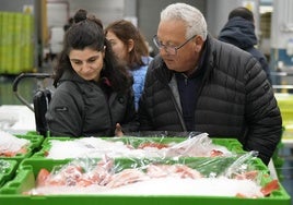 Una mujer y un hombre observan los pescados en cajas congeladas.