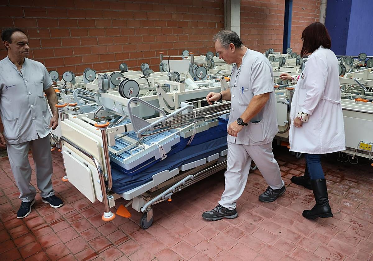 Imagen principal - Trabajadores del Hospital Donostia colaboran para preparar las camas antes de ser transportadas. 