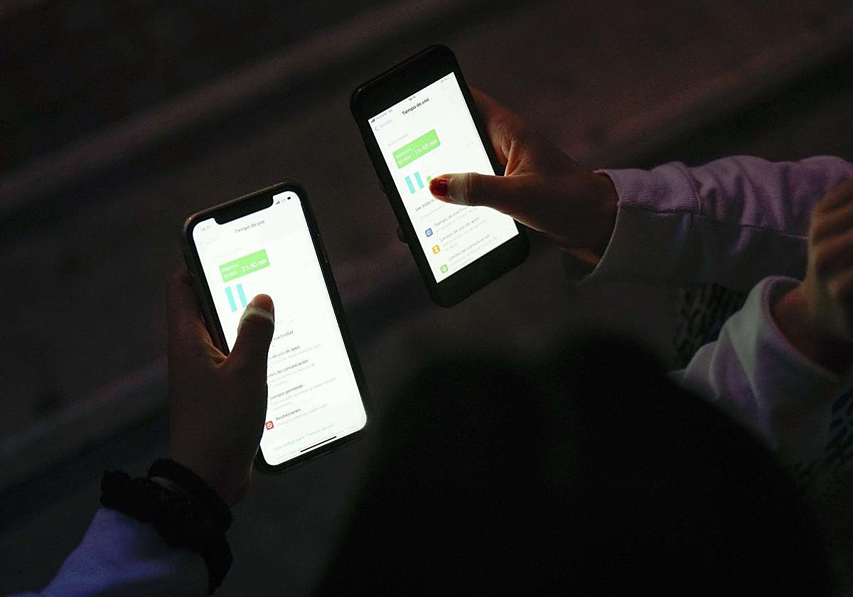 Dos alumnas, con los móviles.