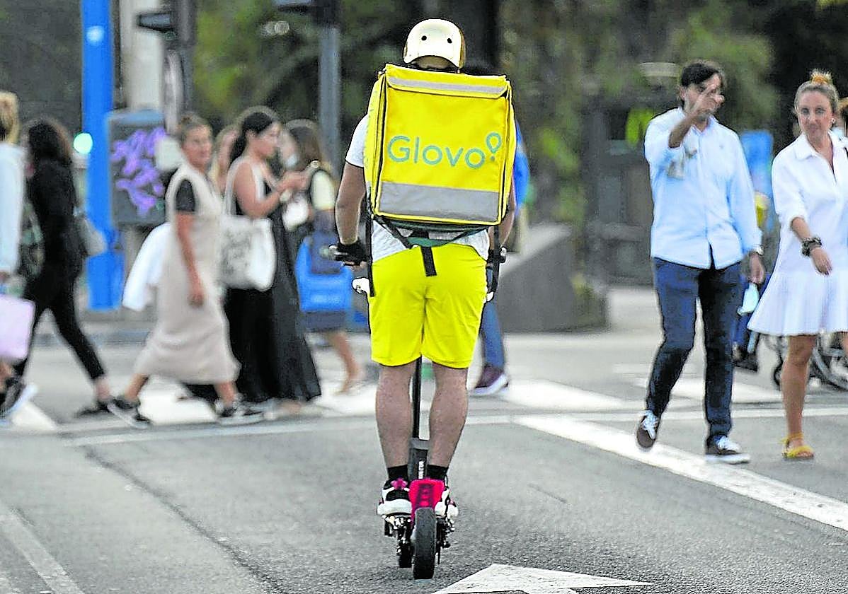 Un repartidor de Glovo, en patinete eléctrico por el centro de San Sebastián.
