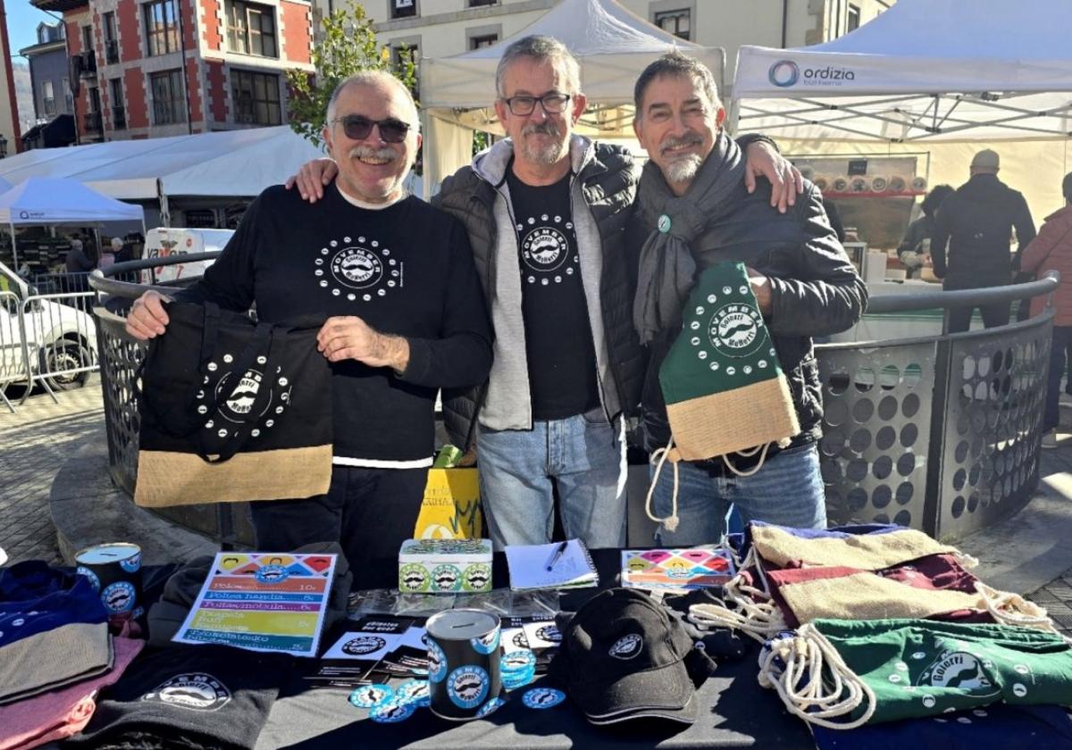 Tres miembros de la plataforma, en el puesto de la feria de Ordizia con el merchandising.