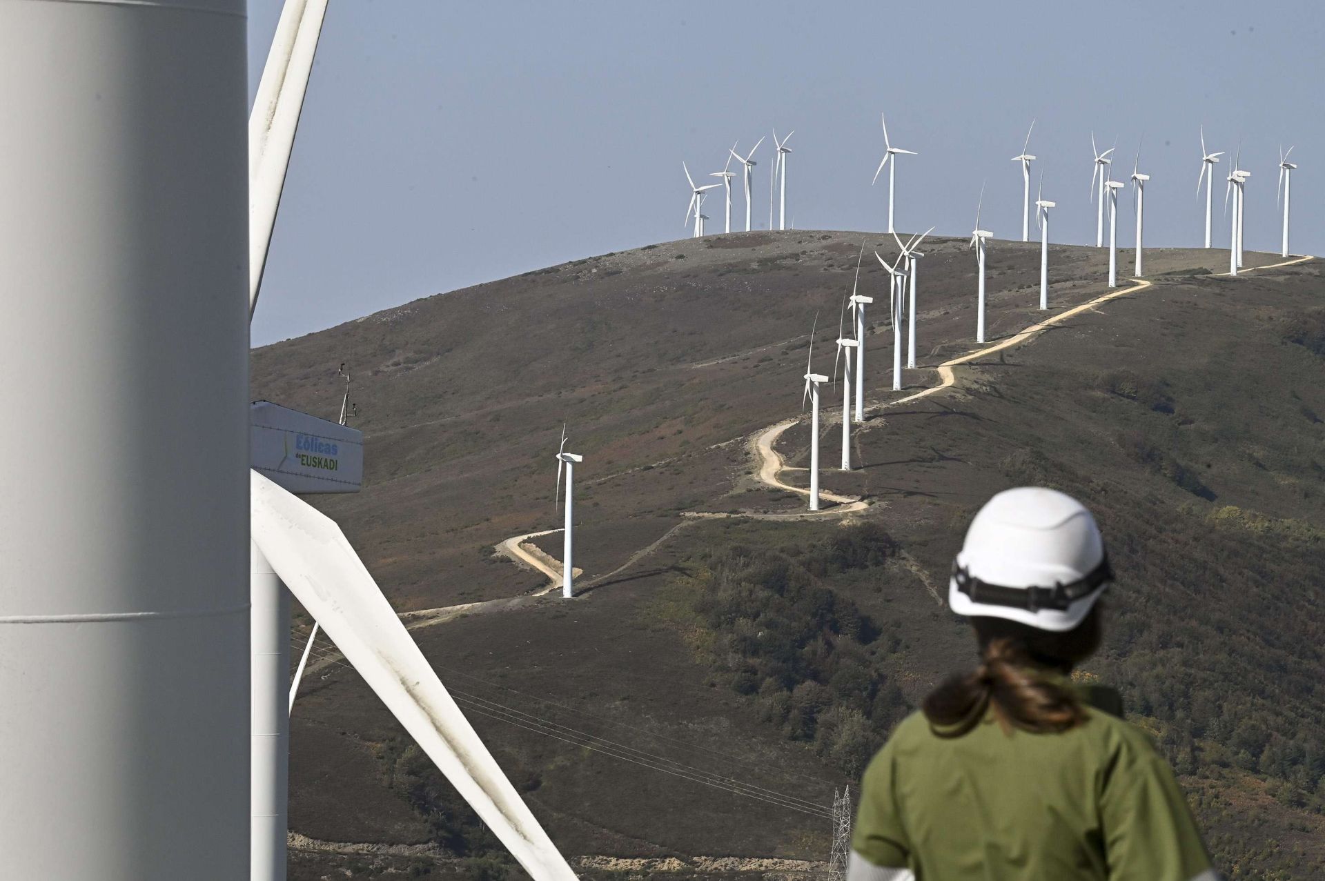 Una trabajadora observa la hilera de molinos de viento en Elguea-Urkilla, entre Araba y Gipuzkoa.