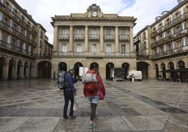 Dos mochileros caminan por la plaza de la Constitución de Donostia.