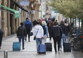 Un grupo de turistas camina por las calles de Donostia con varias maletas.