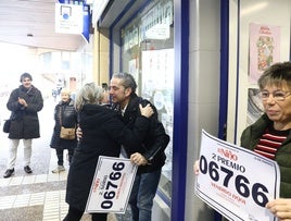 Mikel Garmedia, dueño de la administración que ha repartido el segundo premio, posa junto a sus familiares con el cartel con el número premiado.