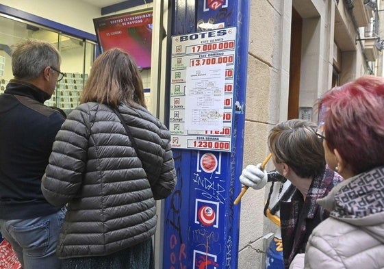 Varias personas comprueban diferentes números premiados en una administración de Loterías.