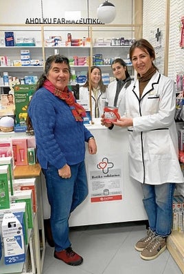 Ainhoa Etxabe, de Caritas, a la izquierda, en la farmacia Elosegi.