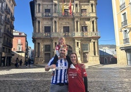 Una familia txuri-urdin y rojilla posa en la plaza del Ayuntamiento de Pamplona.