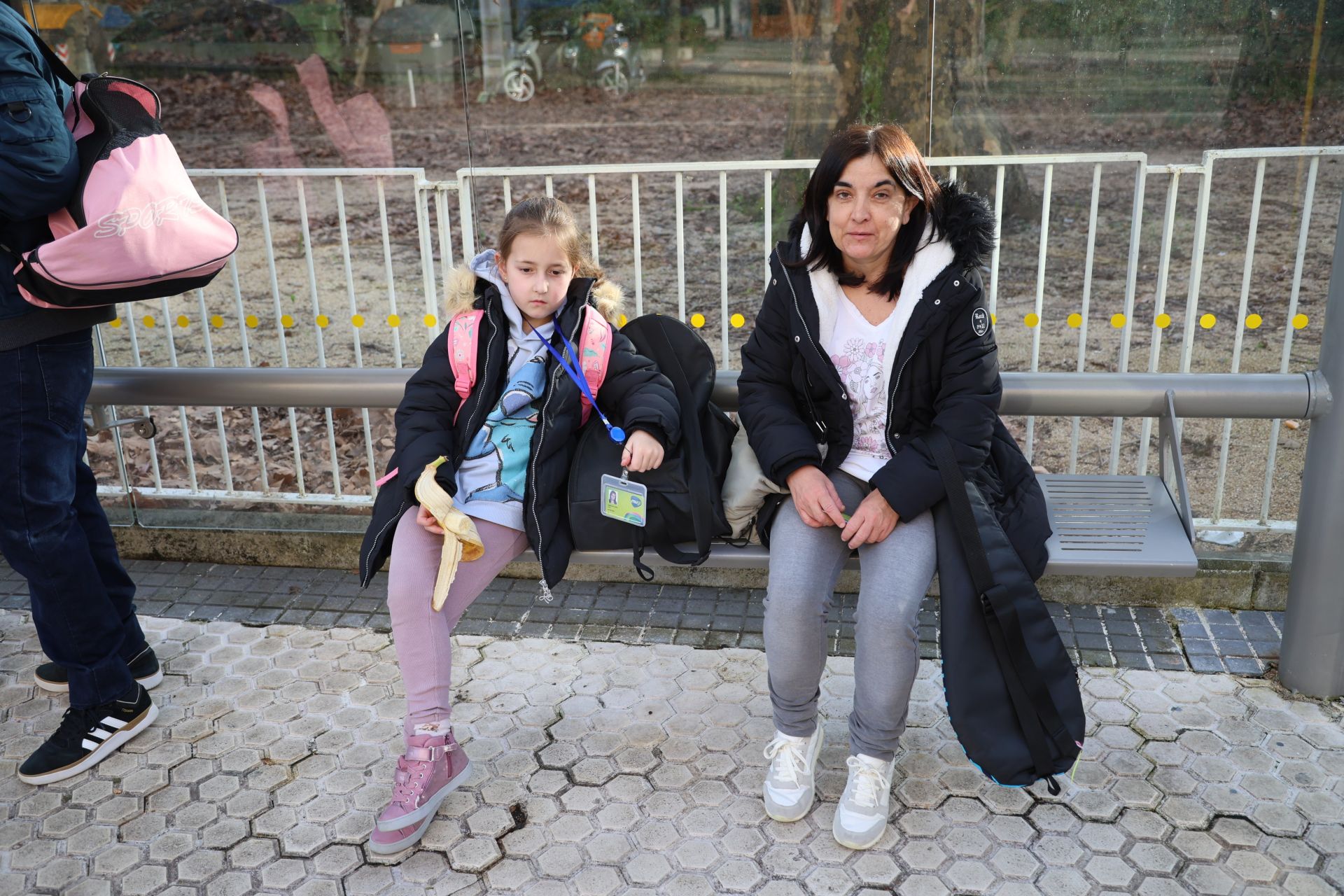 Imagen secundaria 1 - Paula, de 10 años, pasa la tarjeta por el lector. Debajo, Aroa, de 7 años, y su madre, Beatriz López, sentadas en la marquesina.