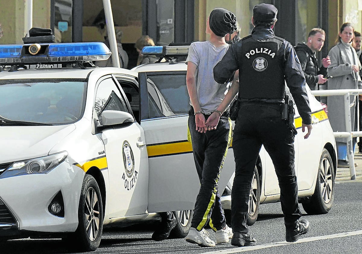 Un guardia municipal procede a arrestar a un joven en el centro de Donostia.