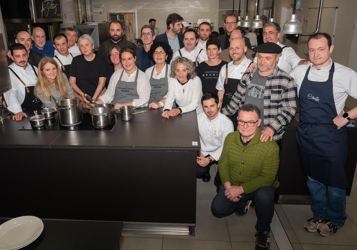 Imagen principal - Foto de familia de los participantes, y Gorka Txapartegi y Lidia Olaizola en plena faena en los fogones.