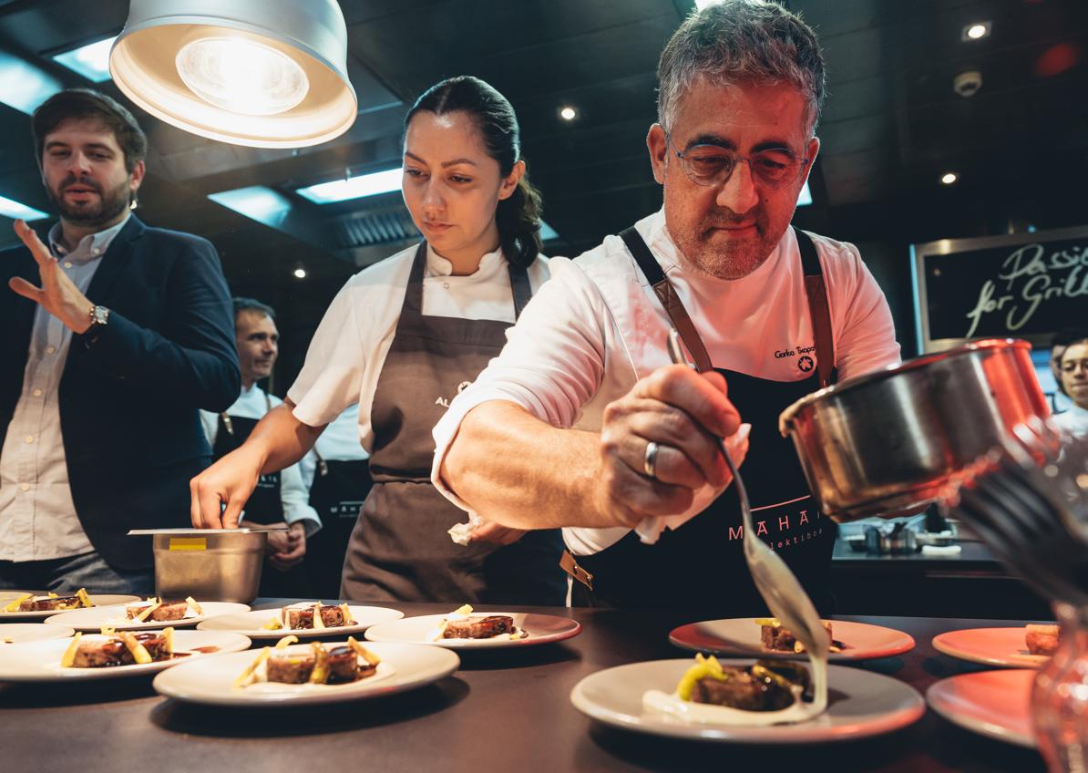 Imagen secundaria 1 - Foto de familia de los participantes, y Gorka Txapartegi y Lidia Olaizola en plena faena en los fogones.