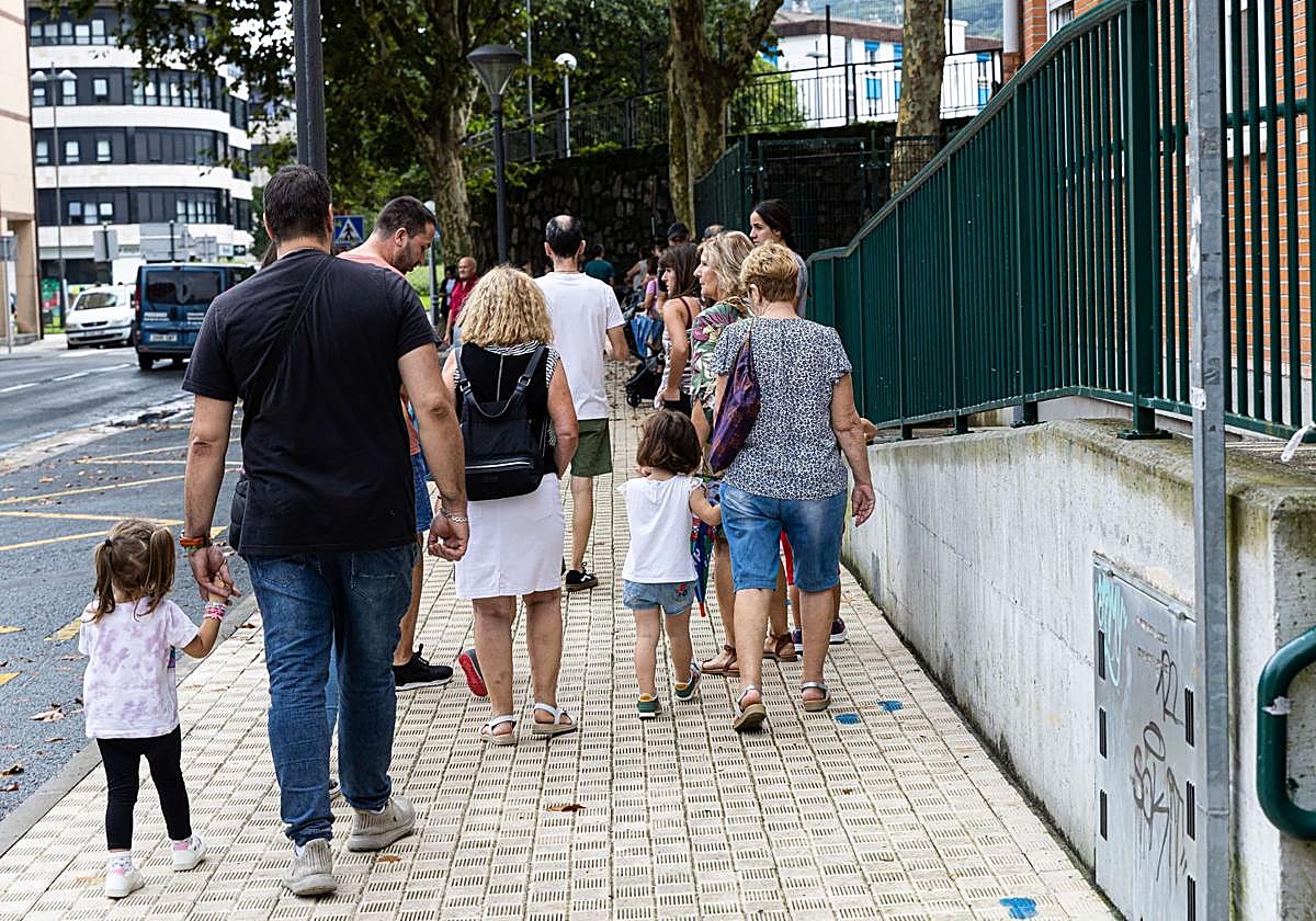 Varias familias acceden a un centro escolar con sus hijos.