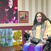 Marta Andreu posa con algunos de los cuadros que ha pintado con la boca tras haber ido perdiendo movilidad por la enfermedad siringomielia.