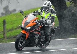 Una moto circula sobre una carretera mojada, terreno delicado para frenar.