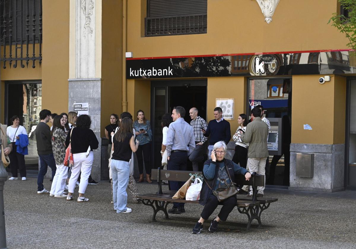 Clientes y trabajadores a las puertas de Kutxabank en Tolosa, durante el apagón del lunes.