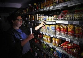 Una clienta ilumina las estanterías de un supermercado con su móvil. durante el apagón.