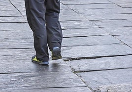 Un viandante esquiva una de las baldosas de pizarra hundidas en la plaza del Triángulo.