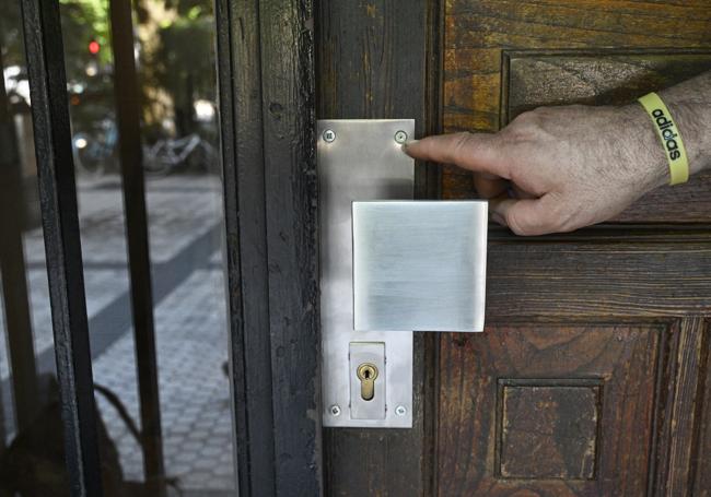 Tirador de acero inoxidable en Donostia con un tornillo condenado en un portal donde el original de latón ha sido robado.