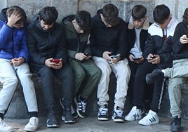 Varios menores jugando con sus teléfonos móviles.
