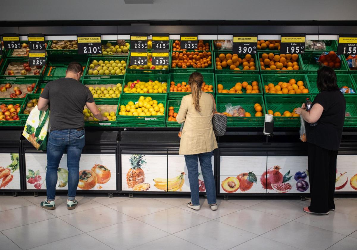 Varias personas realizan la compra en un supermercado.