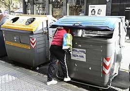 Una persona sin recursos rebusca en un contenedor de basura en Donostia.