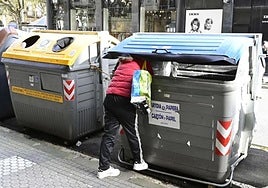 Una persona sin recursos rebusca en un contenedor de basura en Donostia.