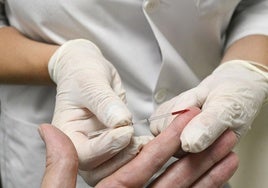 Una farmacéutica toma una muestra de sangre a un paciente para el test.
