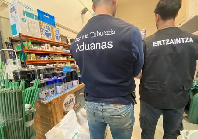 Un agente de la Agencia Tributaria de Vigilancia Aduanera y otro de la Ertzaintza inspeccionan un local