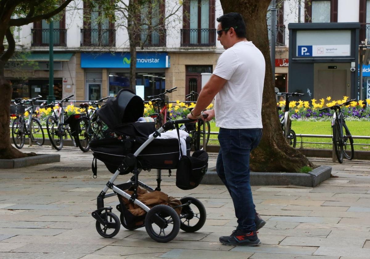 Un hombre pasea a su bebé en carro por el centro de San Sebastián.