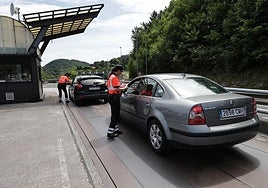 Los dos agentes de tráfico de la Ertzaintza realizan sendas inspecciones a dos turismos junto al peaje de la AP-8 en Irun, sentido Francia.
