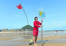 Un socorrista coloca un cartel en la playa de La Zurriola de Donostia.