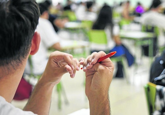 Un joven, sin relación con la información, sujeta un bolígrafo mientras atiende en clase.