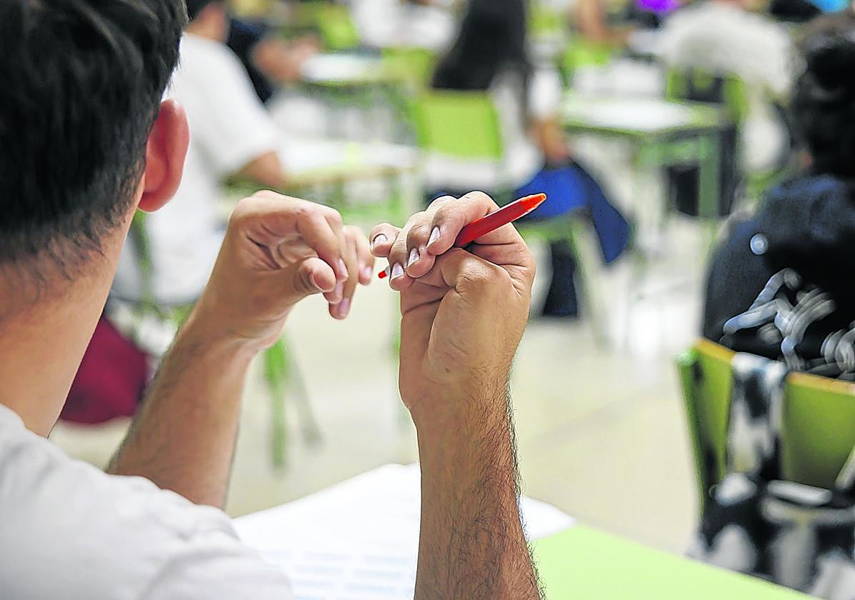 Un joven, sin relación con la información, sujeta un bolígrafo mientras atiende en clase.