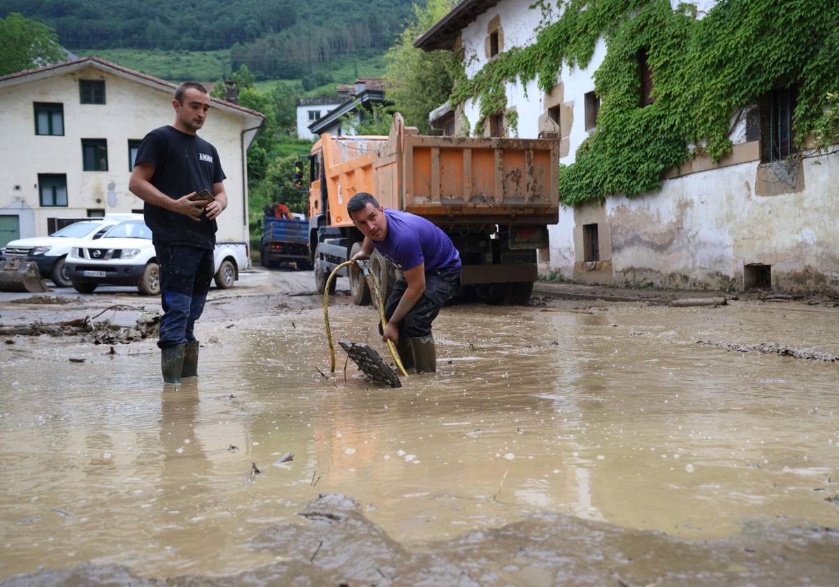 Vecinos de Ataun tratan de achicar el agua en una zona que quedó totalmente inundada.