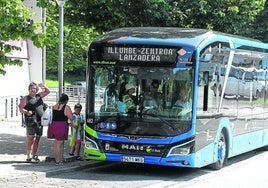 Una familia se dispone a montarse en la parada del bus lanzadera en Illunbe.