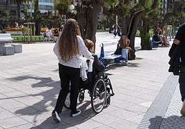 Una joven acompaña a una persona mayor por el centro de San Sebastián.