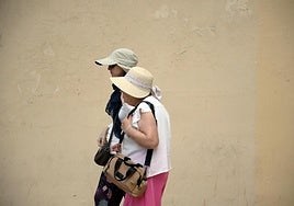 Varias personas se protegen del sol en una calle de Málaga