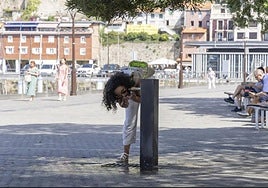 Una joven bebe agua de una fuente pública de San Sebastián.