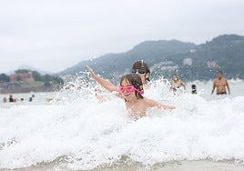 Dos niños -los hermanos Luka y Martina- se divierten en el agua de la playa de La Concha.