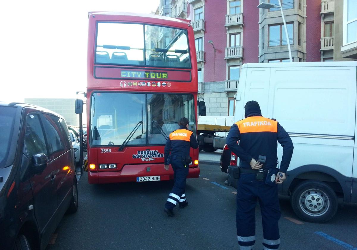 Imagen principal - El bus turístico, atascado en el paseo Salamanca por culpa de una furgoneta que sobresale de la plaza de aparcamiento. Debajo, el agente Igor Ayerdi se baja del coche patrulla para felicitar un cumpleaños durante el confinamiento y dos agentes conversan con una mujer en la Parte Vieja en el primer día del cuerpo, en 2009. 