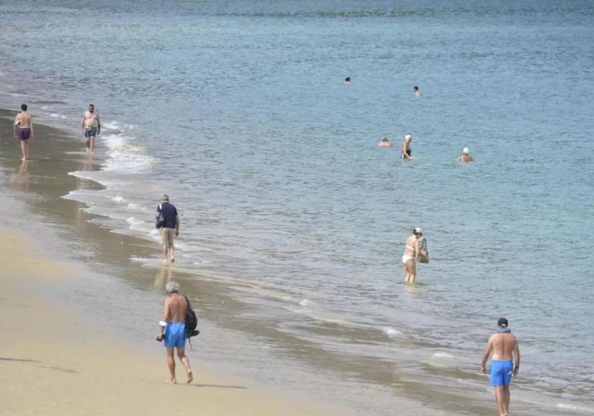 Paseantes y bañistas en una playa.