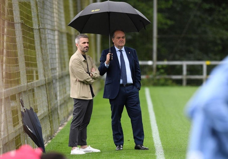 Aperribay, junto a Erik Bretos en el entrenamiento de la Real de este lunes, protegidos de la lluvia por un paraguas