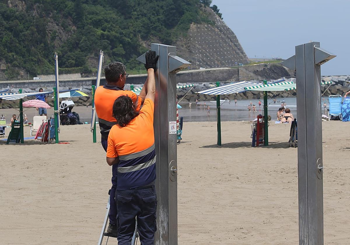 Operarios realizan unos ajustes en las duchas de la playa de Santiago, el pasado verano.