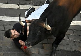 Un mozo es arrollado por uno de los toros de la ganadería Álvaro Núñez durante el tercer encierro de los Sanfermines 2025