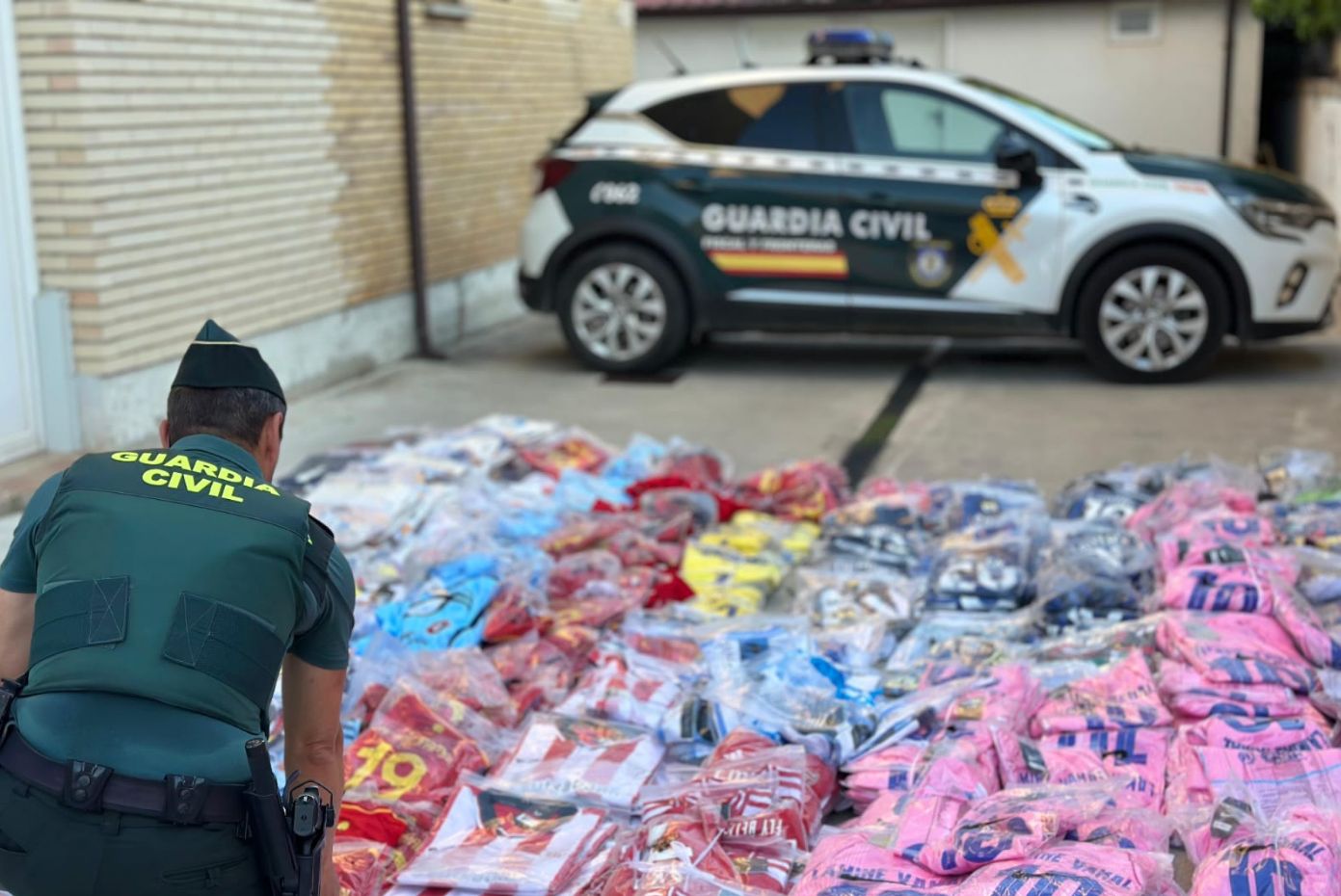 Un agente de la Guardia Civil con parte de las camisetas intervenidas.