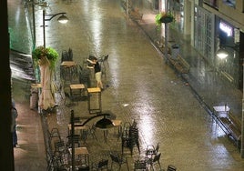 Un hostelero de Eibar recoge la terraza bajo la lluvia.