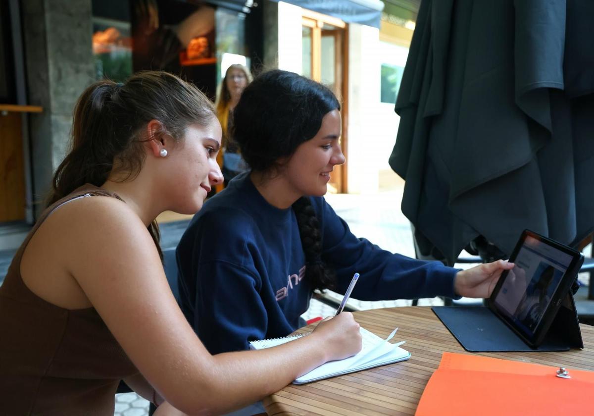 Andrea y Adriana, en una cafetería de Donostia mirando distintas ofertas de grados universitarios.
