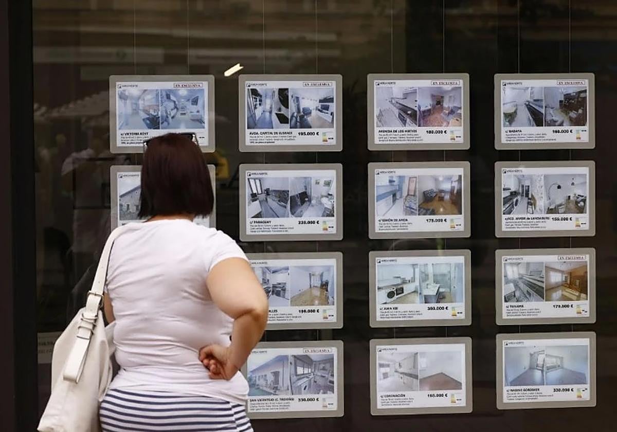 Una mujer observa los anuncios en el escaparate de una agencia inmobiliaria