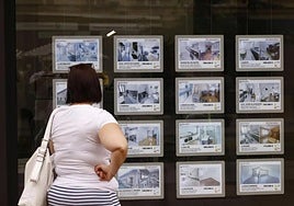 Una mujer observa los anuncios en el escaparate de una agencia inmobiliaria